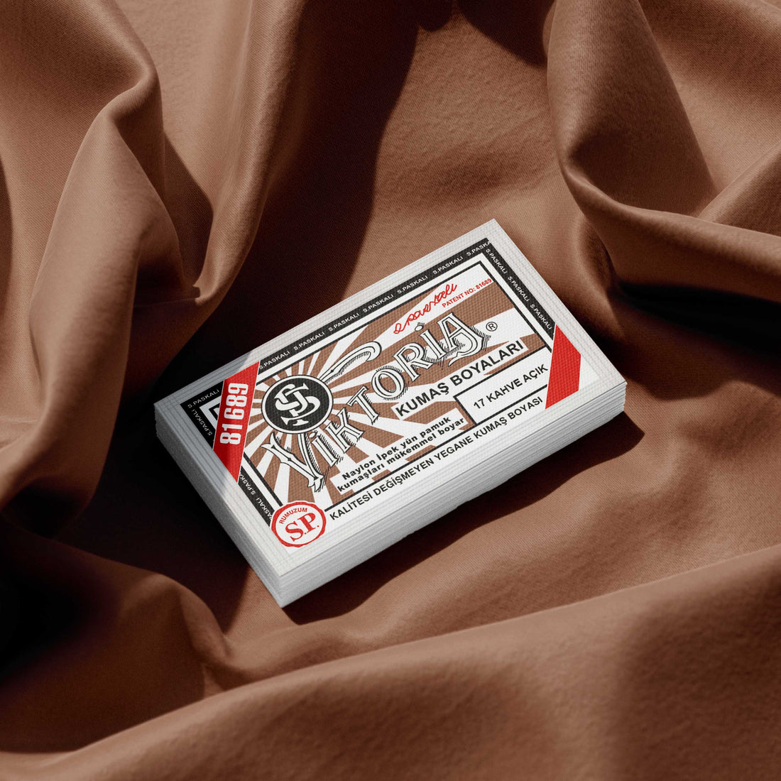 Pack of clay brown fabric dye placed on a vibrant brown fabric background